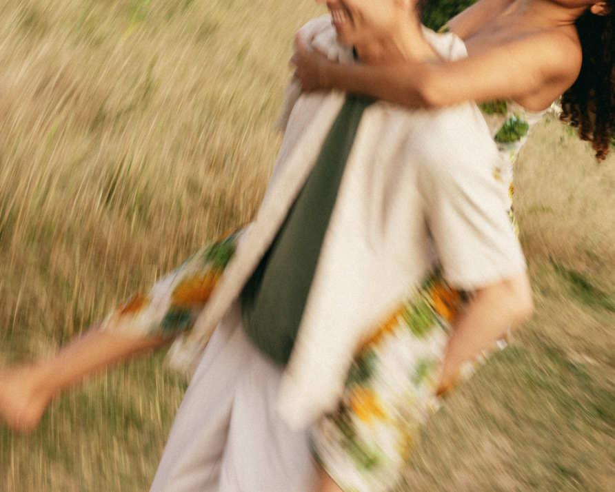 Motion-blurred photo of one person giving another a piggyback ride in a grassy field.